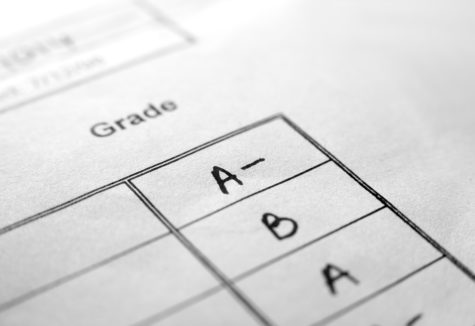 A close-up shot shows handwritten grades including A-, B, and A on a printed report card