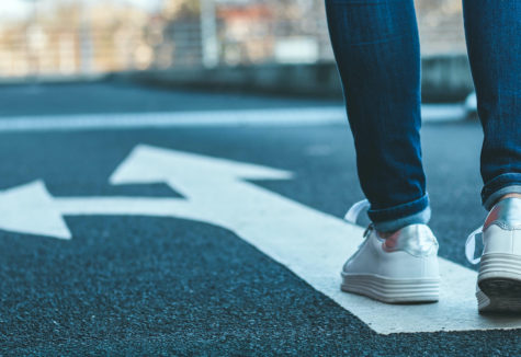 A woman walking on a path with an arrow pointing both forward and to the left
