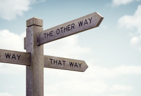 Wooden signpost with multiple arrows pointing in different directions labeled “This Way,” “That Way,” and “The Other Way.”