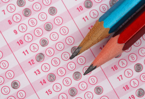 Two sharpened pencils rest on a multiple-choice answer sheet filled with darkened bubbles