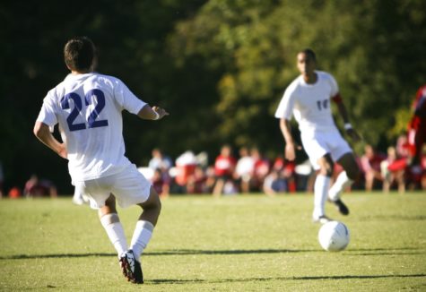 Two soccer teammates passing the ball in the middle of a soccer match