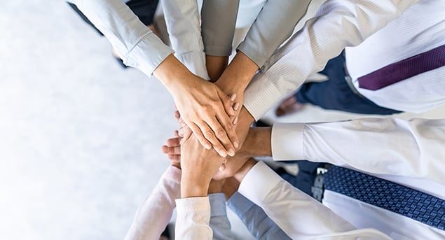 Group of professionals stacking hands in a teamwork gesture