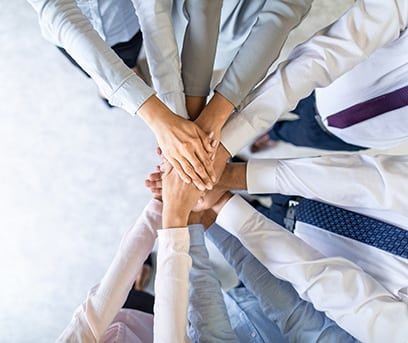 A group of professionals stacking hands in a teamwork gesture