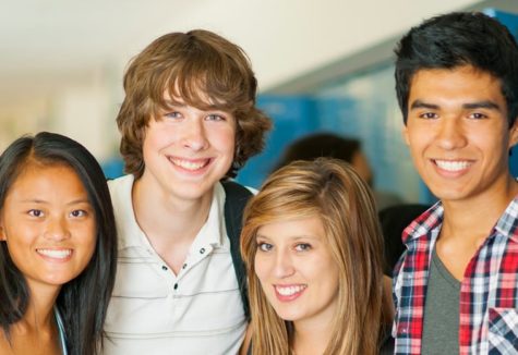 A group of smiling high school students standing by lockers