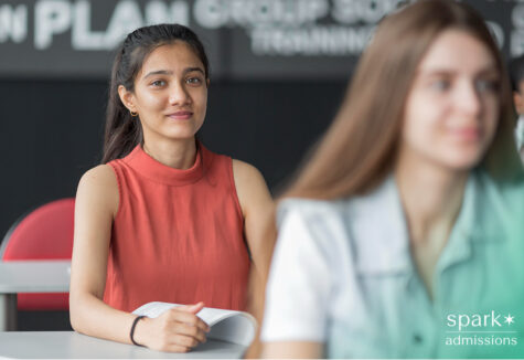 High school student in classroom reviewing materials during college admissions preparation