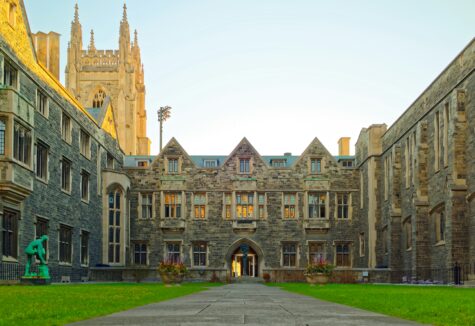 Courtyard of a historic university building with gothic architecture and green lawn