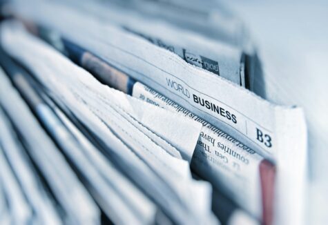 Folded newspapers stacked closely, with a visible "World Business" section headline