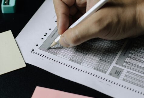 Hand filling in bubbles on a standardized multiple-choice answer sheet with a pencil