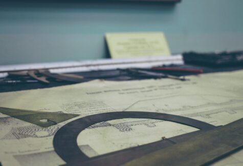 Drafting tools laid out on an old engineering blueprint in a workspace