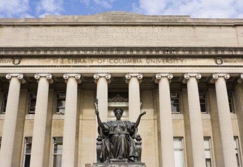 The front of Columbia University's library features tall columns and a statue in the foreground