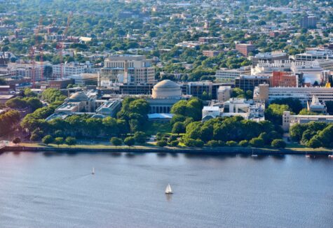 An aerial view of the MIT campus in Cambridge shows domed buildings along the river