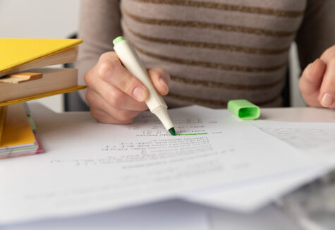 Close-up of a student using a green highlighter while studying math problems