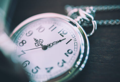 Close-up of a silver pocket watch showing the time with a blurred background