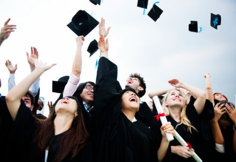 Graduates in caps and gowns celebrating by throwing their graduation hats into the air