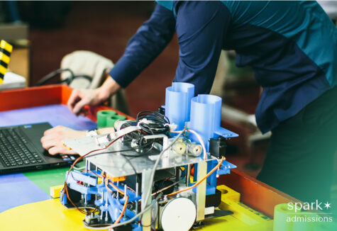 A student works on a project for engineering beside a laptop