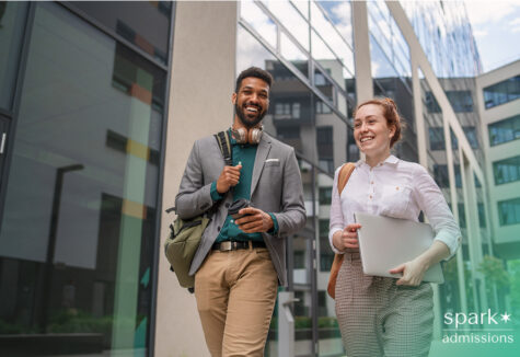 Two students smile while walking outside a modern academic building