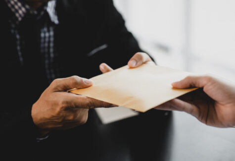 A person hands over a sealed envelope to another person