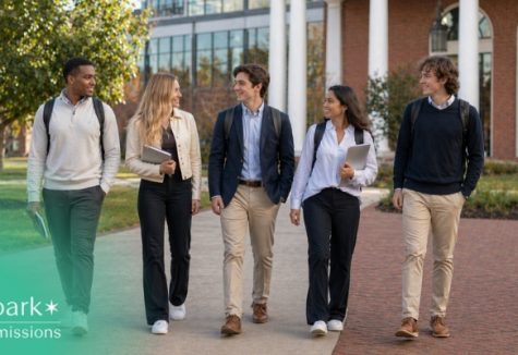 Group of college students walking together across campus with backpacks and laptops in front of an academic building
