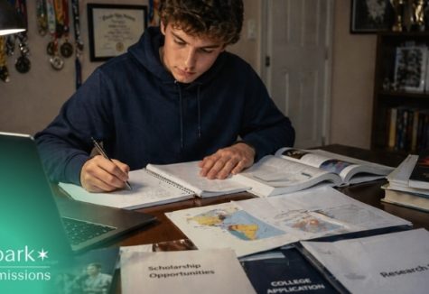 Student studying at a desk with notebooks, a laptop, textbooks, and college application materials.